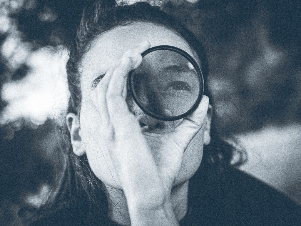 Teilnehmerin eines Fotokurses von Peter Podpera blickt mit einem Auge durch einen Polarisationsfilter um dessen Wirkungsweise zu verstehen